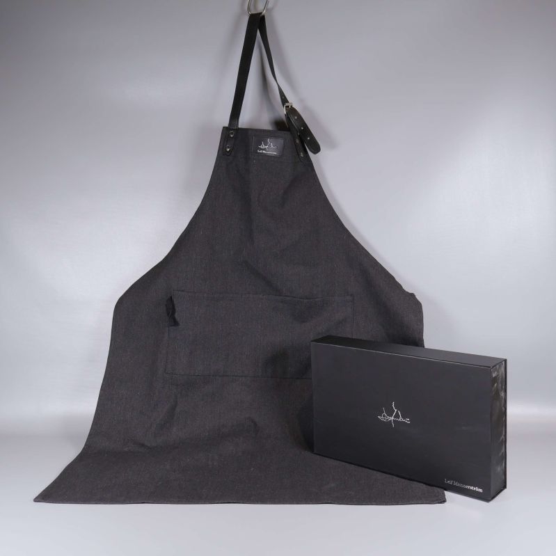 Mörkt förkläde i tyg med presentförpackning bredvid