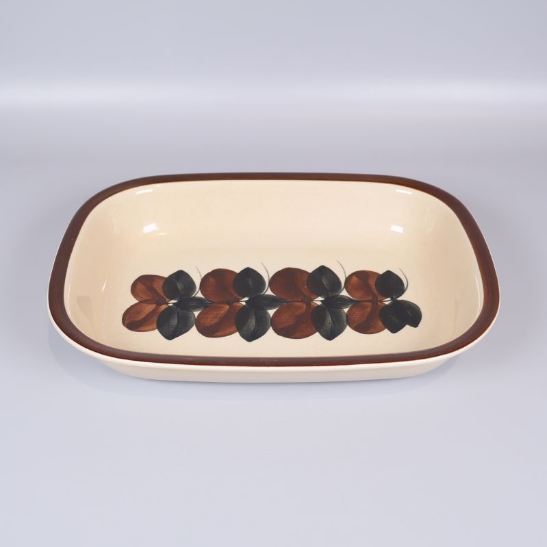 Rektangulär form med brunt och svart bladmönster mot beige botten