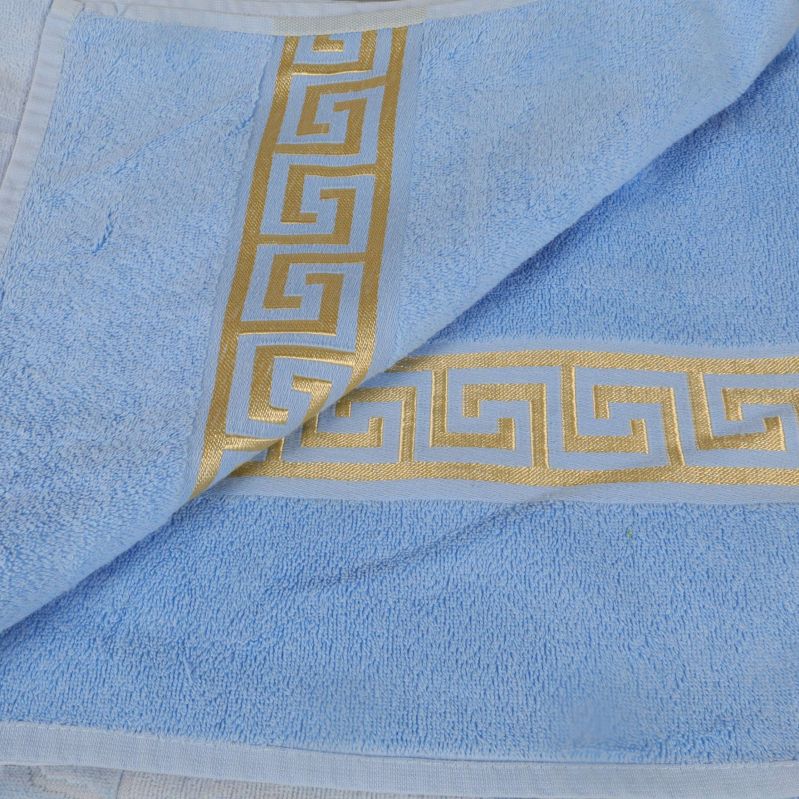 Närbild av handdukens grekisk mönstrad gulddekor