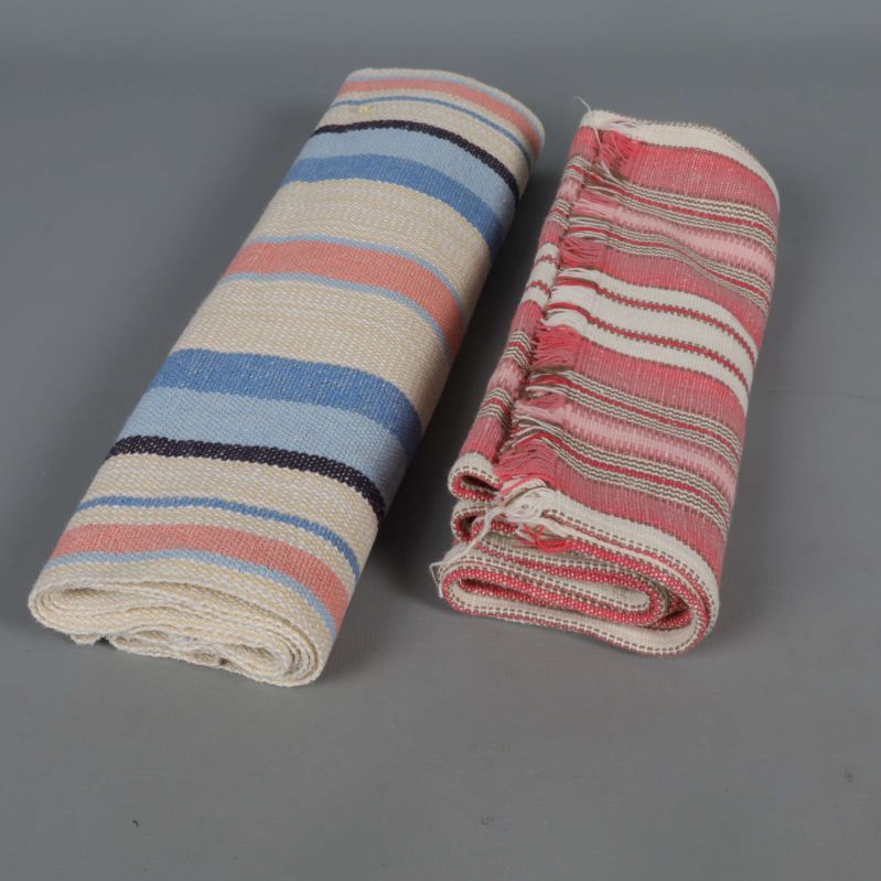 Två hoprullade löpare i olika färger på grå bakgrund