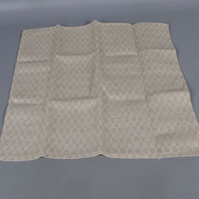 Enstaka servett utlagd och vikt i rutigt beige tyg