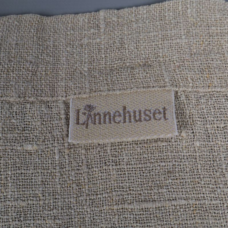 Textiletikett med Lynnehuset påsydd på duken