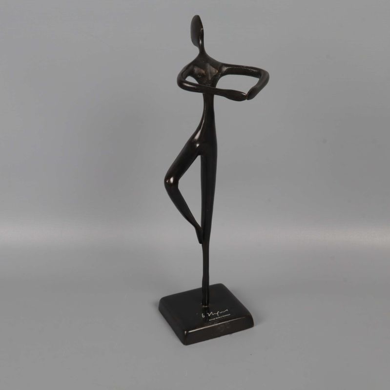 Abstrakt mörk skulptur av dansande figur på fyrkantig fot