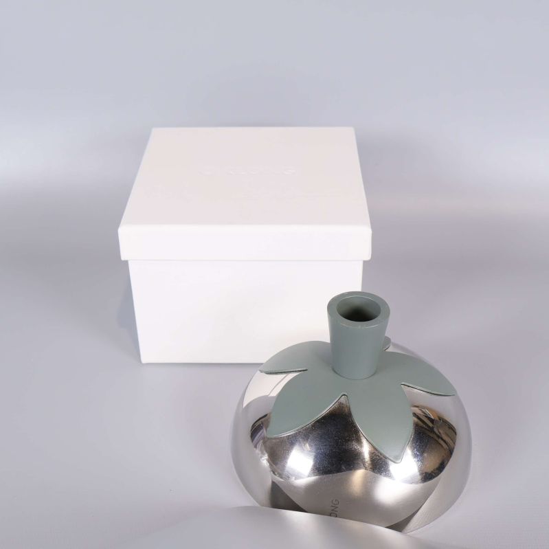 Ljusstake med bladform och vit förvaringsask bakom