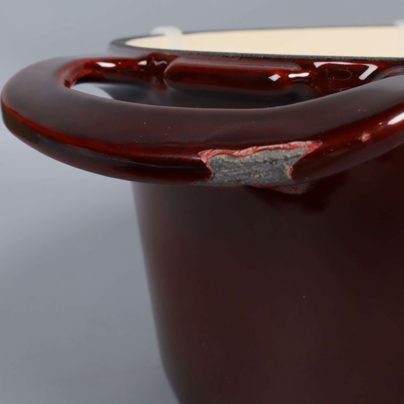 Närbild på skadad emalj vid handtag på grytan