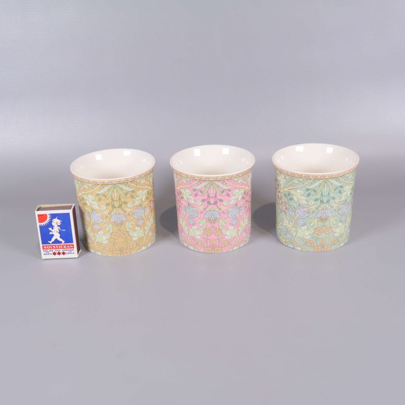 Tre blommiga muggar uppställda bredvid tändsticksask