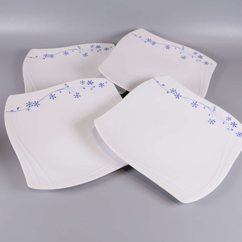 Fyra vita tallrikar med kurviga former och blå blommönster