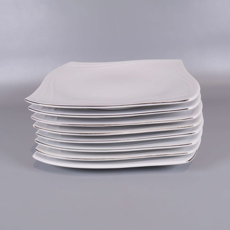 Sida av staplade vita fyrkantiga tallrikar mot grå bakgrund