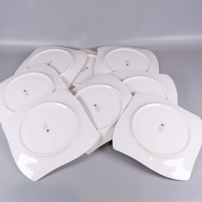 Åtta vita tallrikar med undersidan synlig, blå logotyp