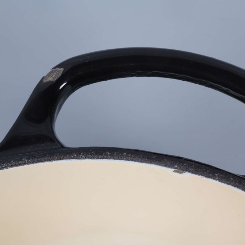 Närbild på handtag med skav i emaljen och svart yta