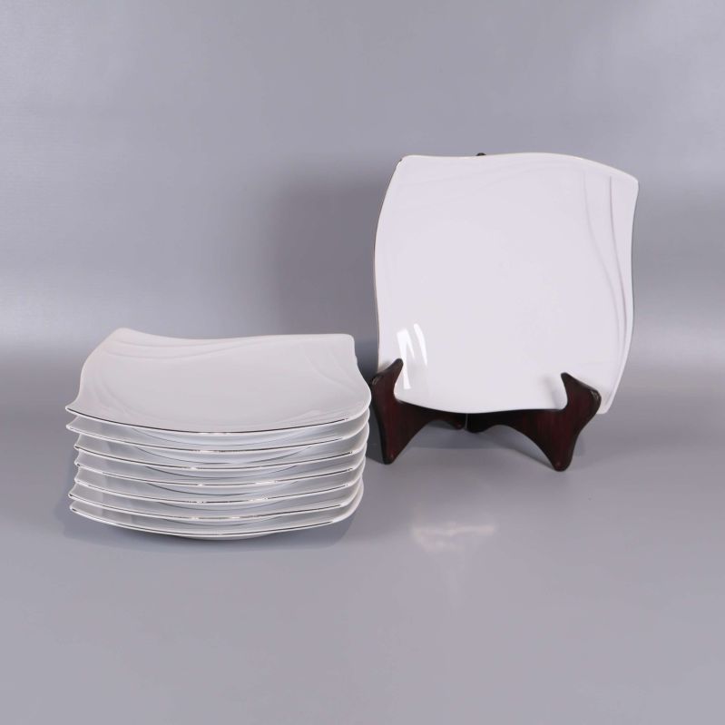 Åtta vita vågformade assietter, en på ställ