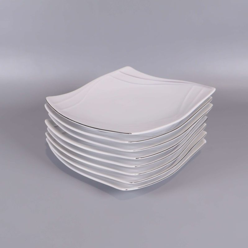 Staplade vita vågformade assietter i set om åtta