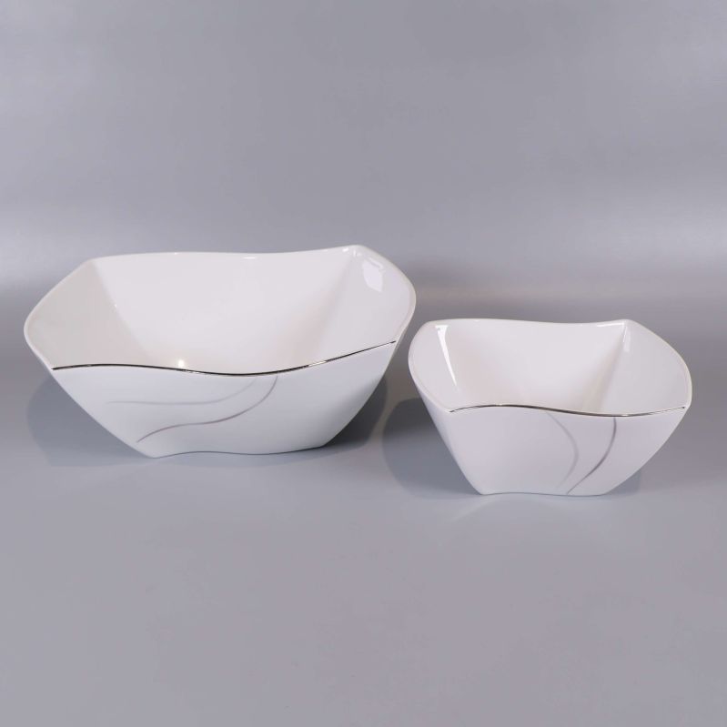 Två fyrkantiga vita skålar med silvriga detaljer