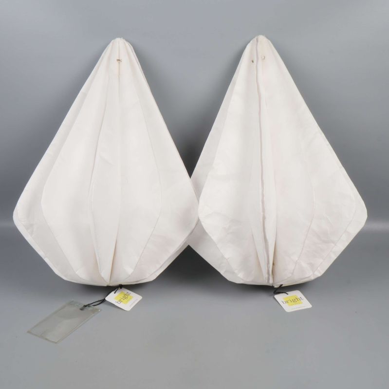 Två vita lampskärmar placerade intill varandra mot grå bakgrund