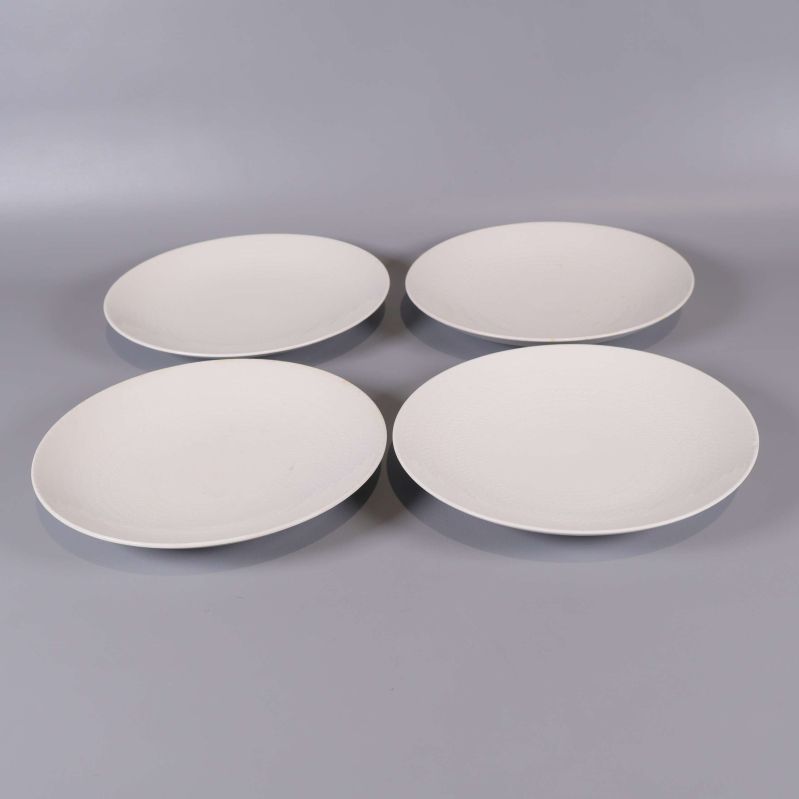 Fyra vita assietter i enkel uppställning på grå bakgrund