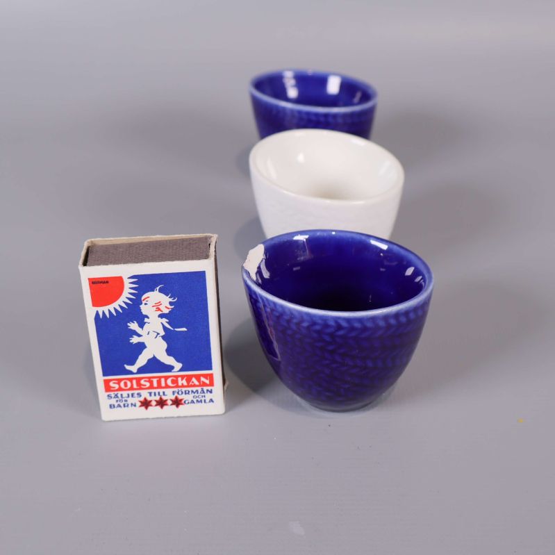 Äggkoppar i porslin bredvid tändsticksask för storleksreferens