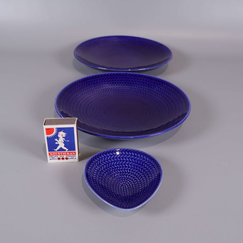 Tre blå serveringsdelar bredvid tändsticksask för skala