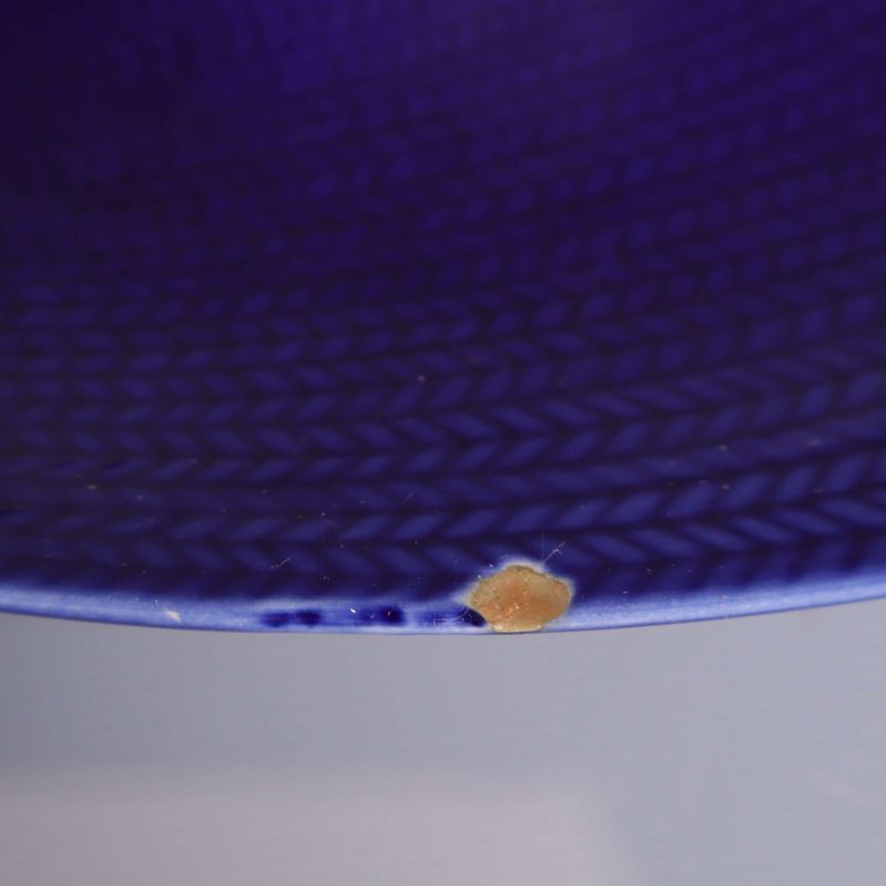 Närbild på nagg på kanten av blått fat