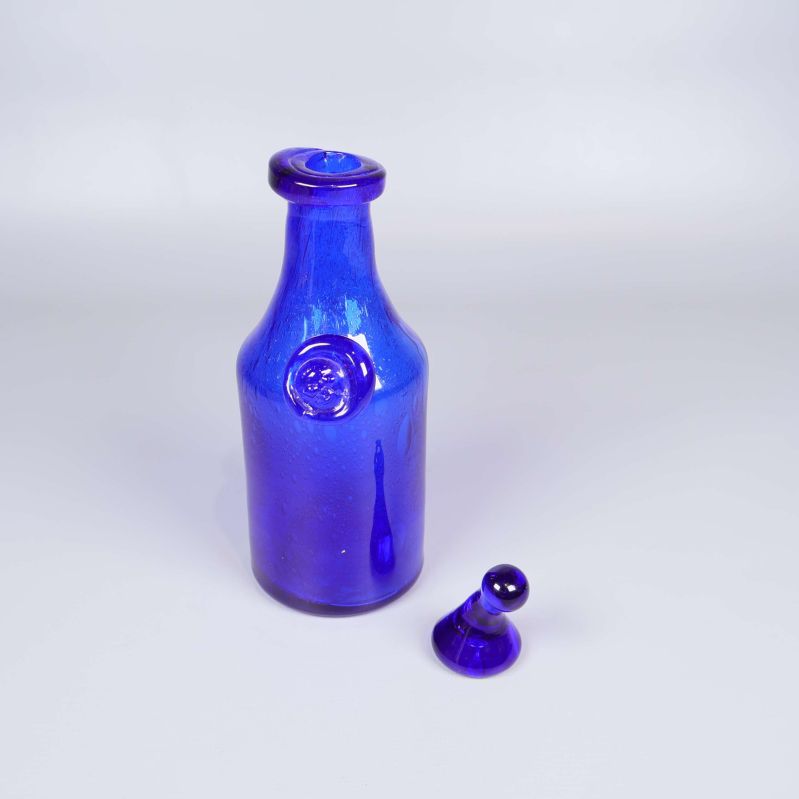 Handblåst blå glasflaska med propp bredvid