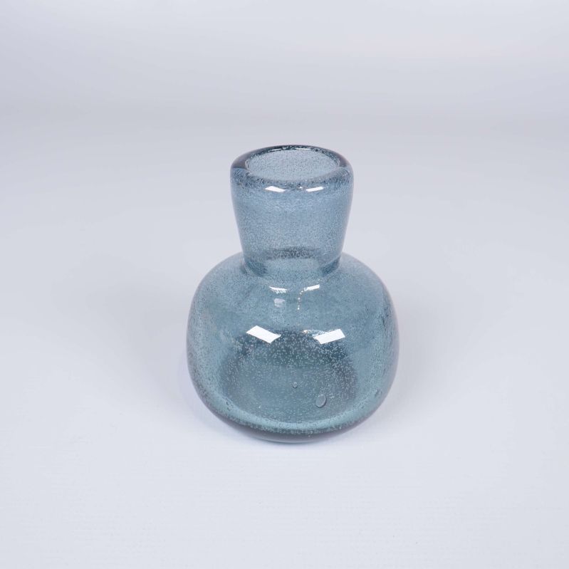Liten blå glasvas med bubblor fotograferad framifrån