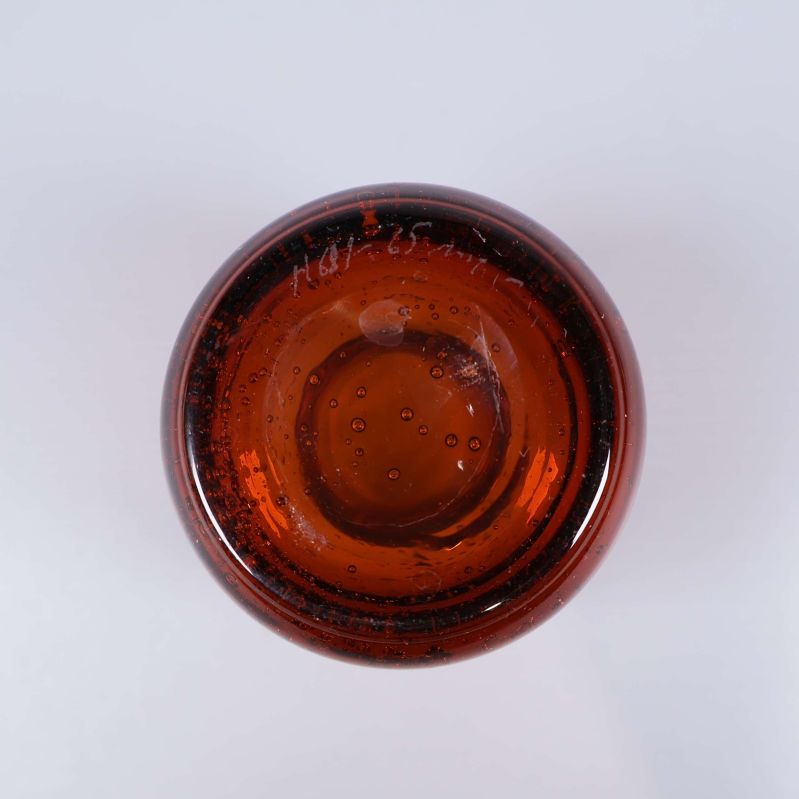 Botten av den bärnstensfärgade glasvasen med luftbubblor
