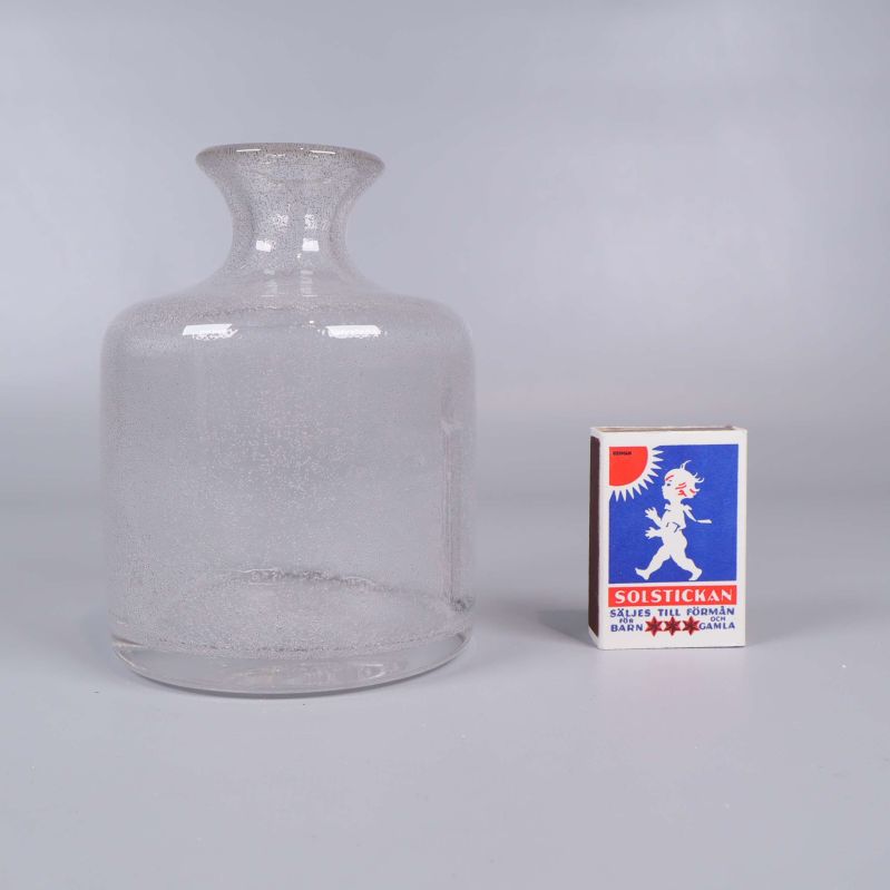 Klar glasvas bredvid tändsticksask för storleksjämförelse