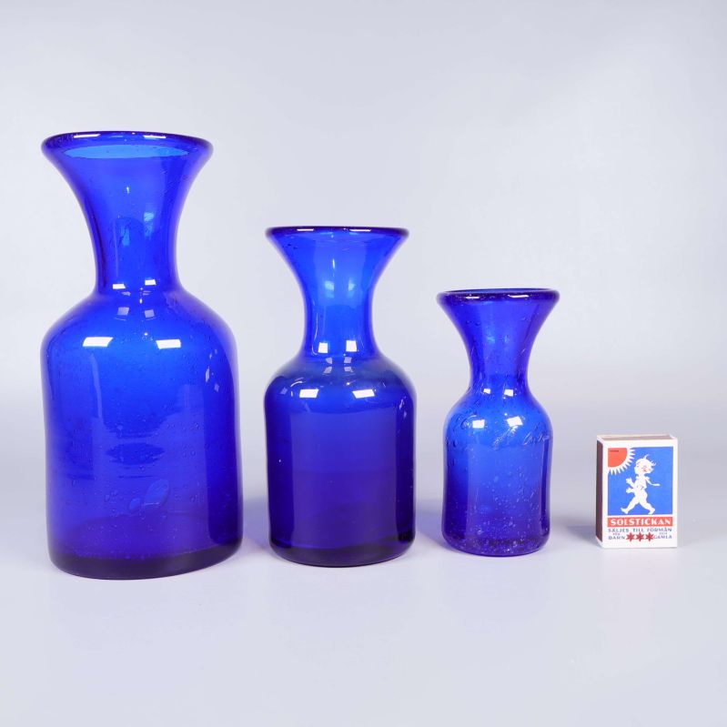 Blå glasvaser i olika storlekar bredvid tändsticksask