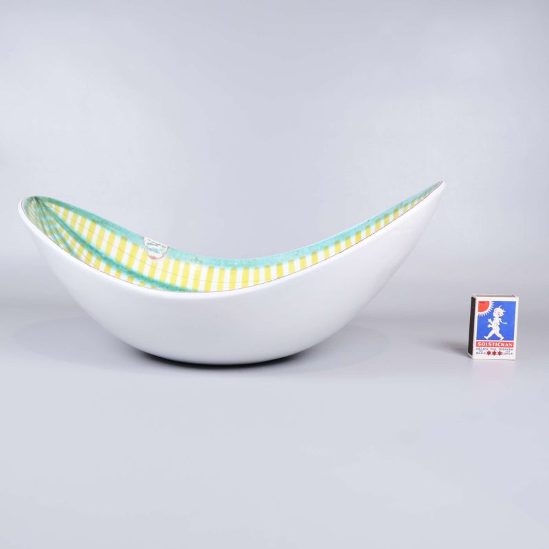 Skålens profil med randigt mönster och vit utsida intill tändsticksask