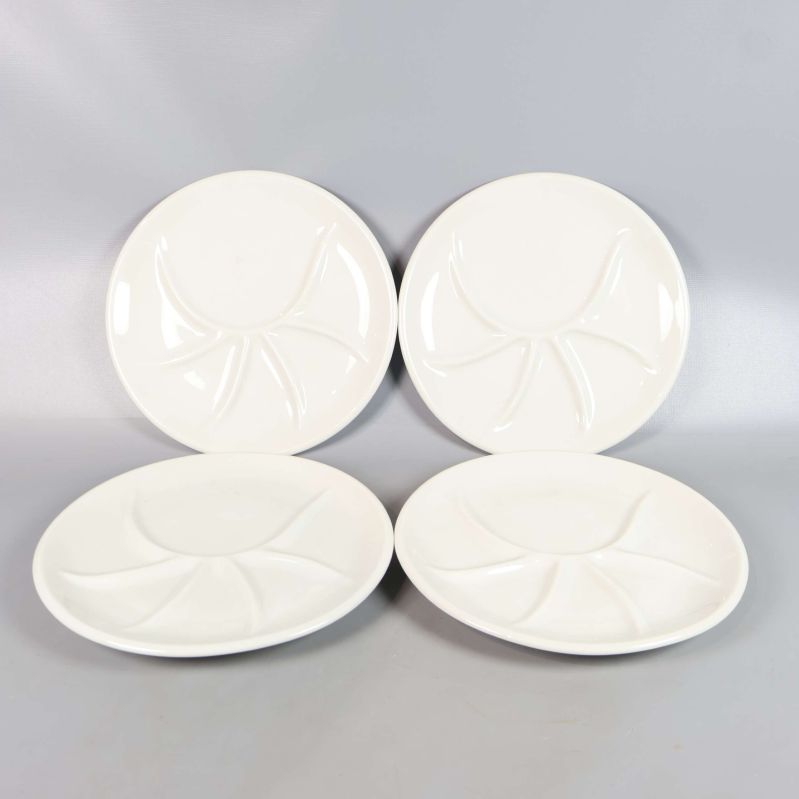 Två stående och två liggande vita tallrikar med fack