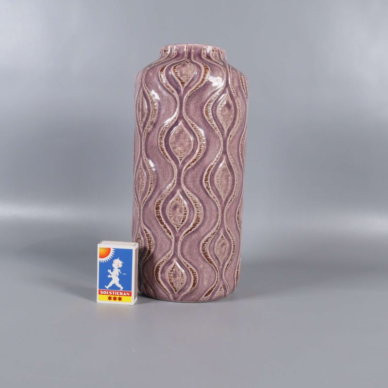 Vas stående bredvid tändsticksask för storleksreferens