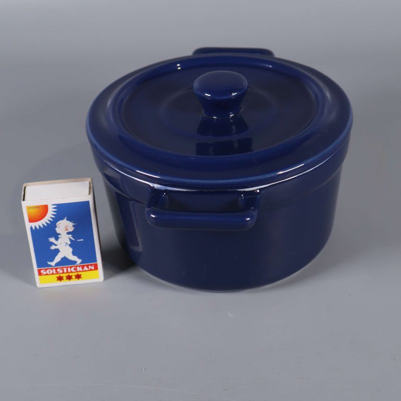 Blå gryta med lock och tändsticksask bredvid för storleksjämförelse