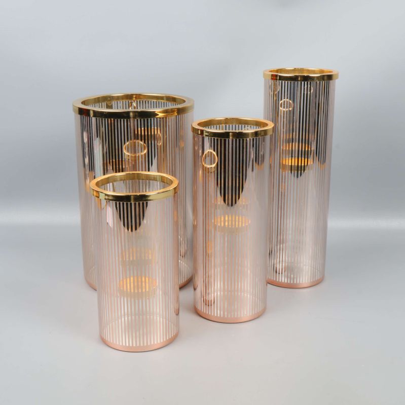 Fyra cylinderformade ljuslyktor med guldiga detaljer