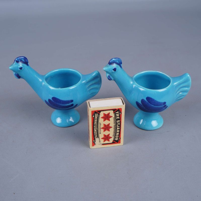 Två blå äggkoppar i form av fåglar med tändsticksask