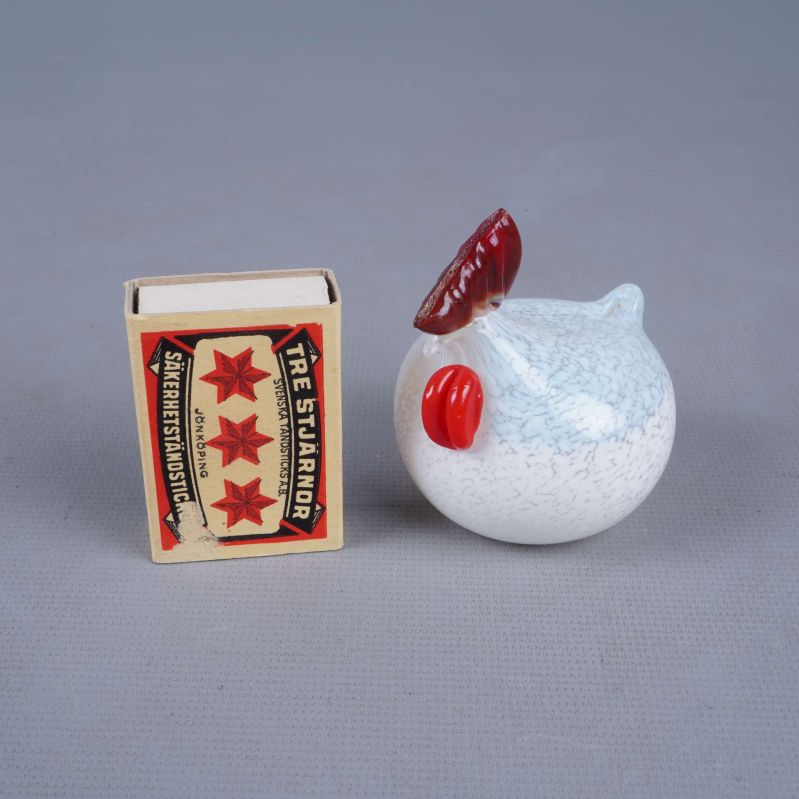 Vit glashöna bredvid tändsticksask för storleksreferens