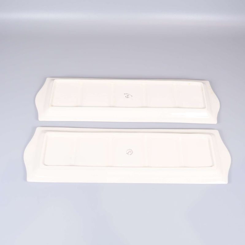 Baksidor av två vita fat med märkning i mitten