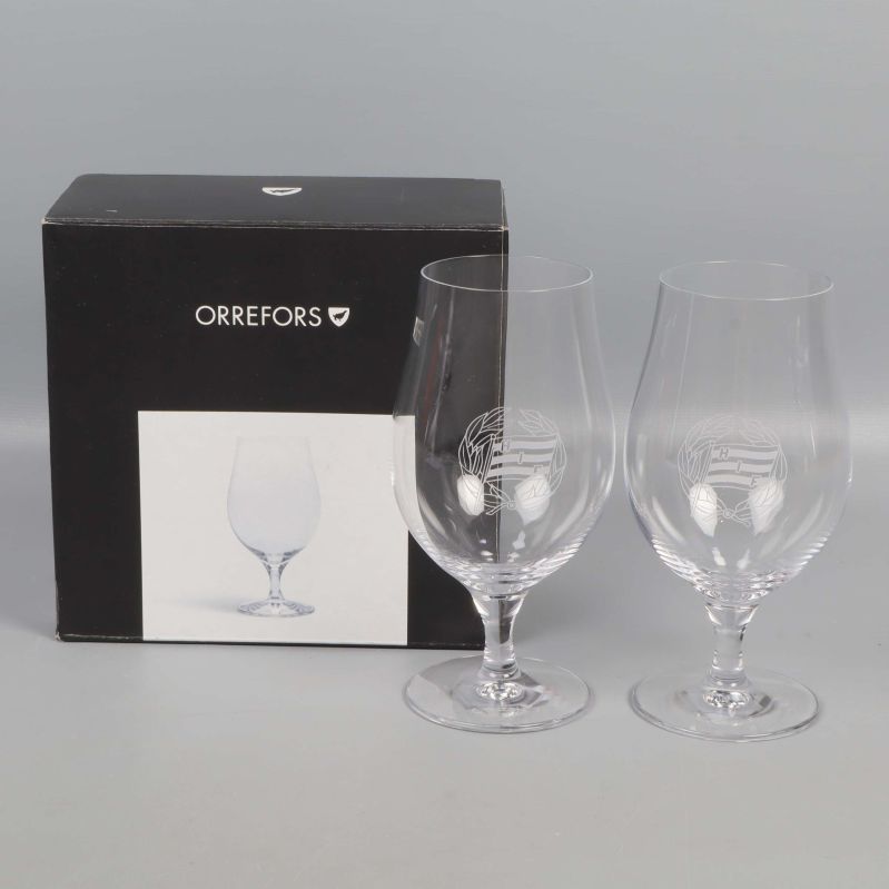 Två ölglas med graverad dekor framför svart kartong från Orrefors