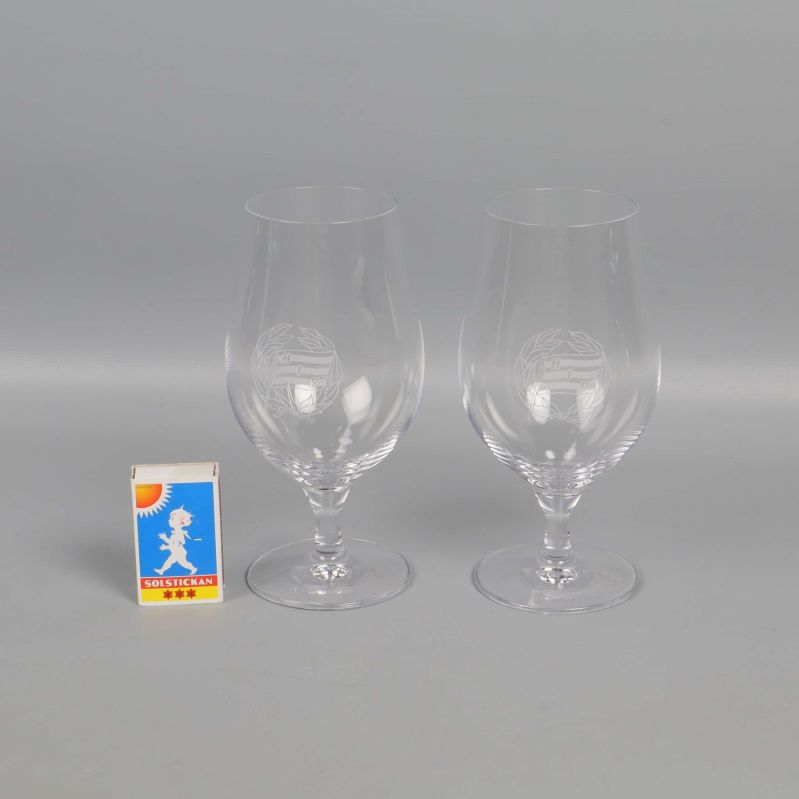 Två ölglas med graverad dekor bredvid tändsticksask