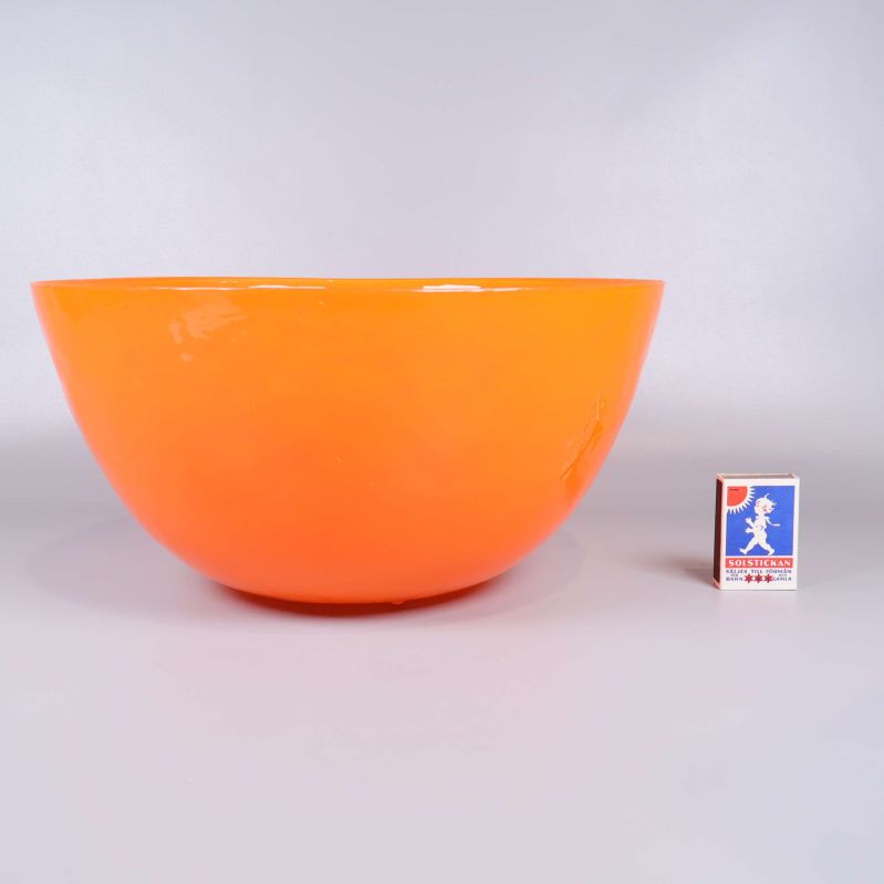 Orange skål bredvid tändsticksask för storleksreferens