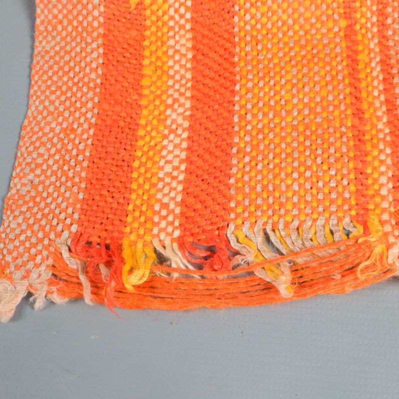 Detaljbild på kant av orange och gulrandig löpare