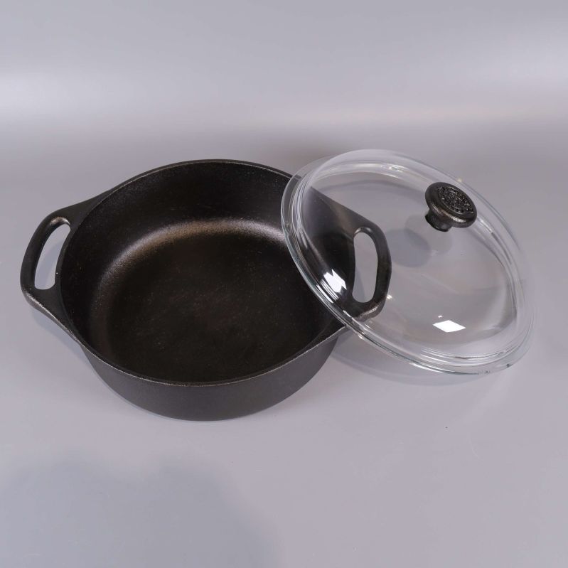 Öppen gjutjärnsgryta med löst glaslock bredvid