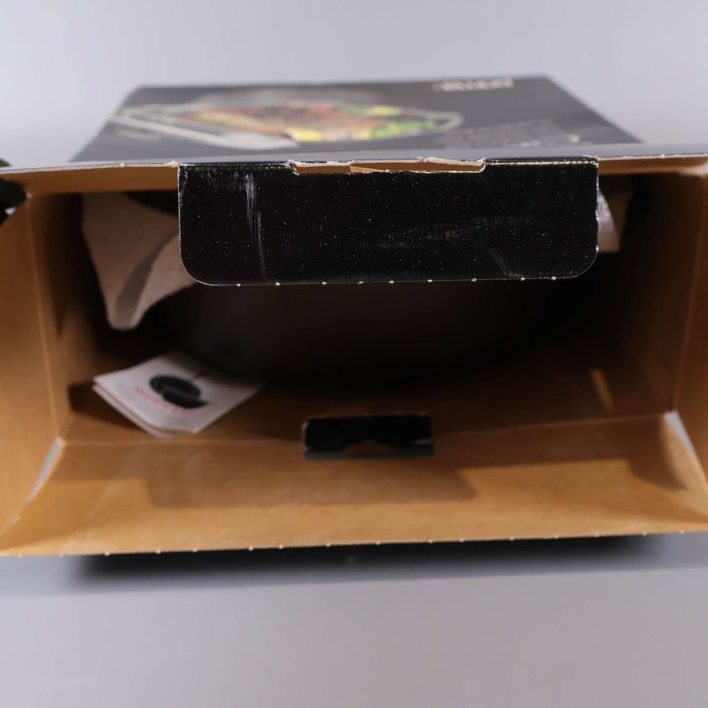 Gjutjärnsgryta och lock i en öppen kartong