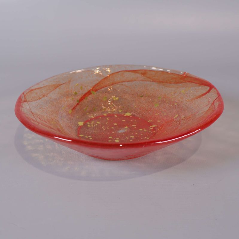 Rödorange glasfat med guldprickar mot ljus bakgrund