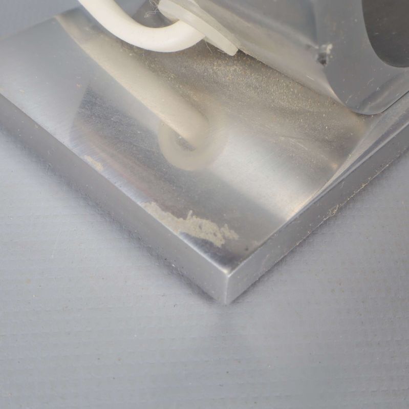 Närbild på lampfot i metall med lätt ytslitage