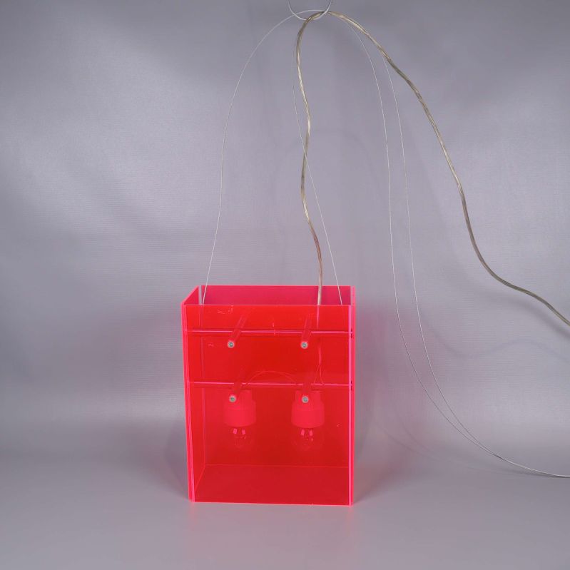 Hängande neonröd taklampa med genomskinliga sladdar