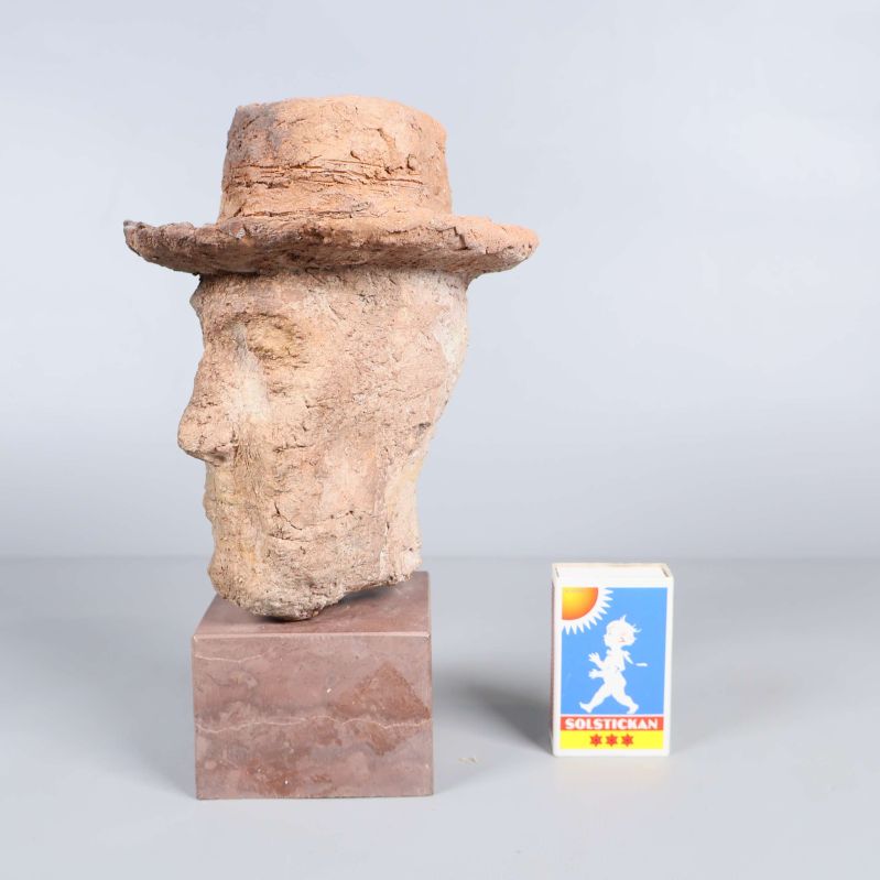 Skulptur i profil bredvid tändsticksask som storleksjämförelse