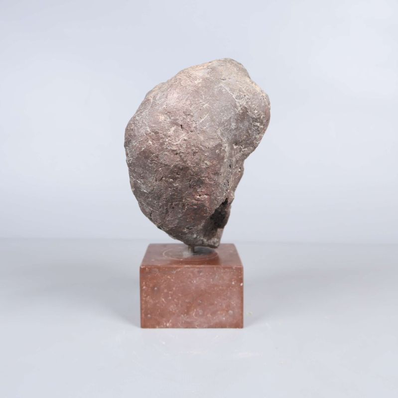 Baksidan av huvudskulpturen på stensockel syns i närbild