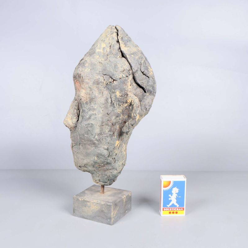 Sidosikt av huvudformad skulptur med tändsticksask bredvid