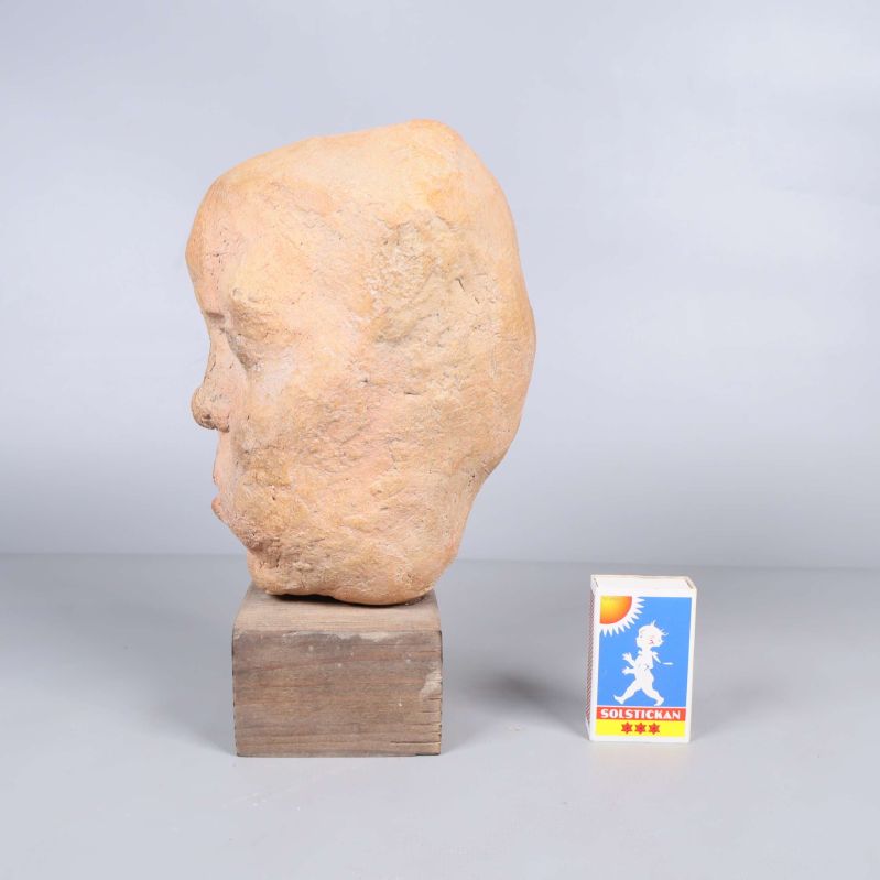 Skulptur av huvud sedd från vänster med tändsticksask bredvid