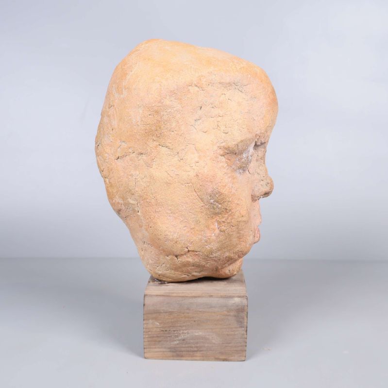 Skulptur av huvud sedd från höger på träfot