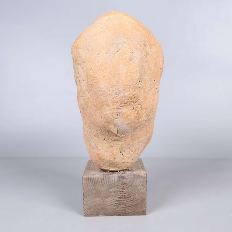 Skulptur av huvud sedd bakifrån på träfot